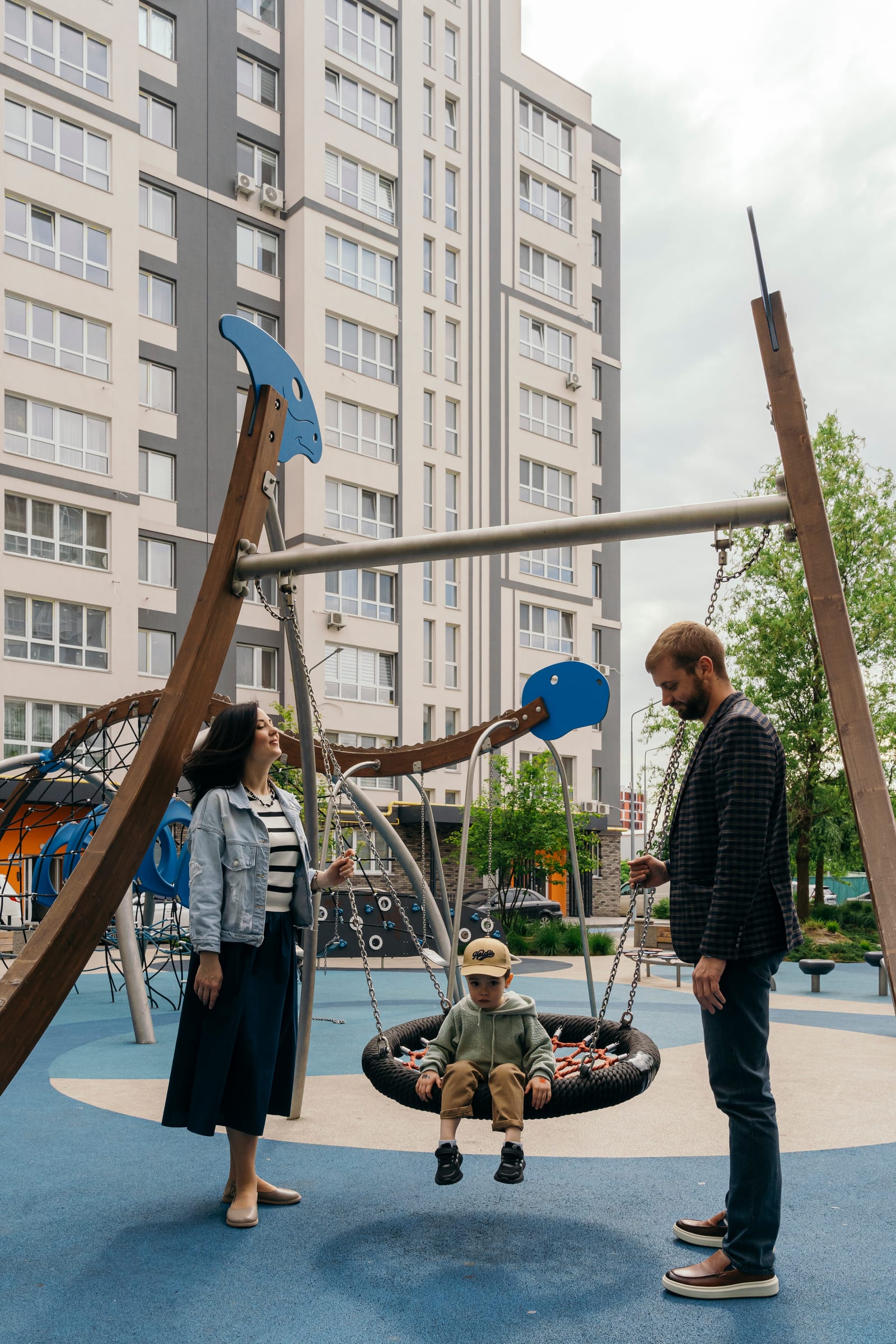 A family with a small child at the nest swing on the playground of a SAVO district