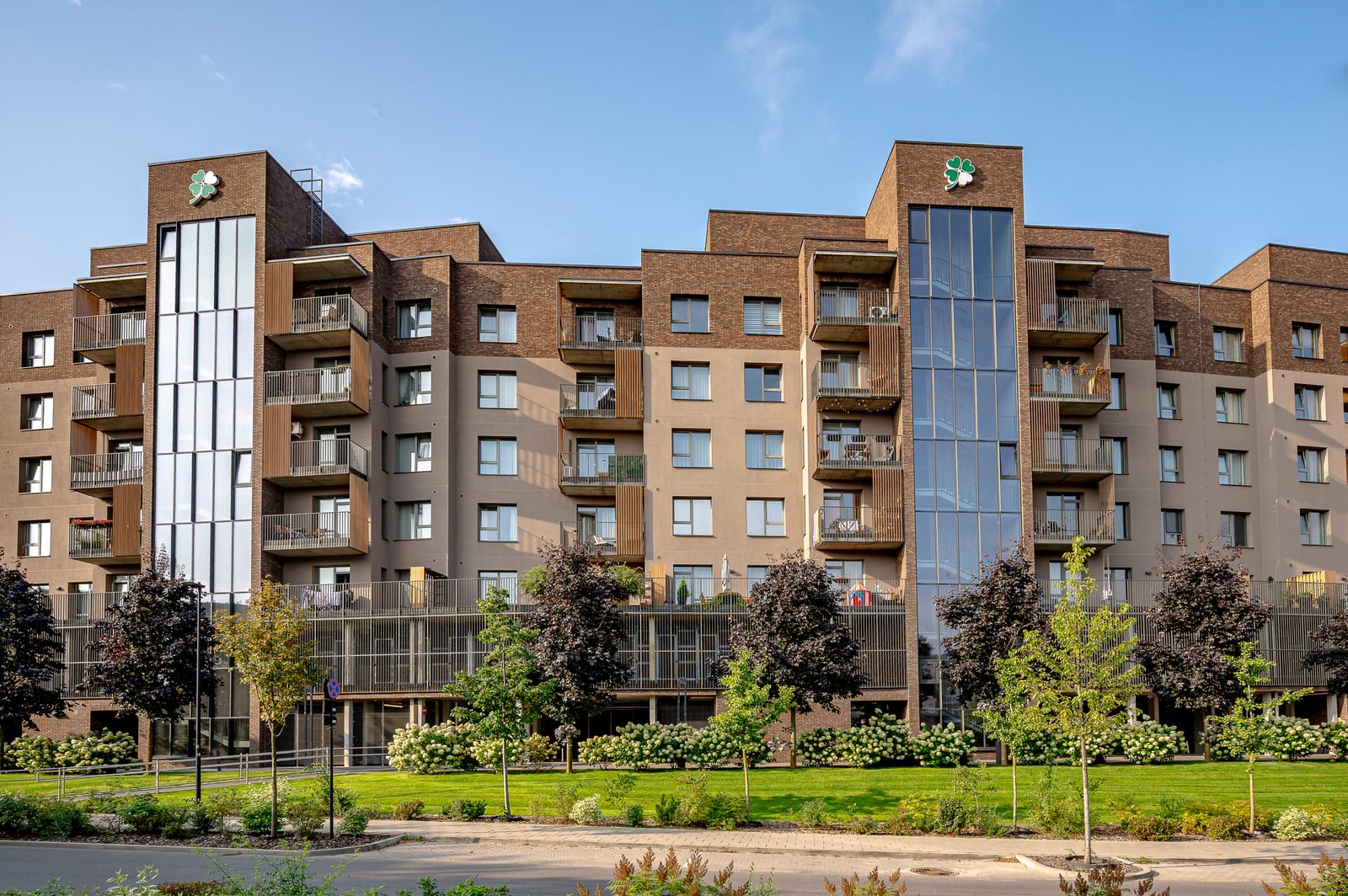 Lucky Homes by SAVO in Vilnius: a clinker-brick residential building with glazed stair towers above landscaped grounds